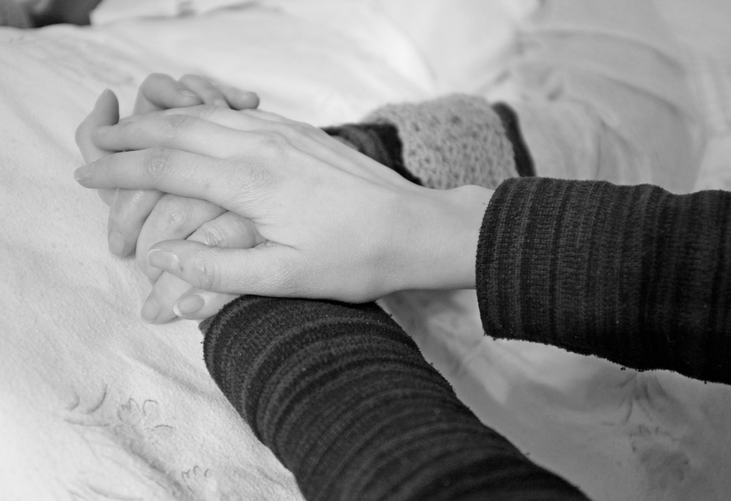 Ein Seelsorger besucht eine kranke Person am Krankenbett