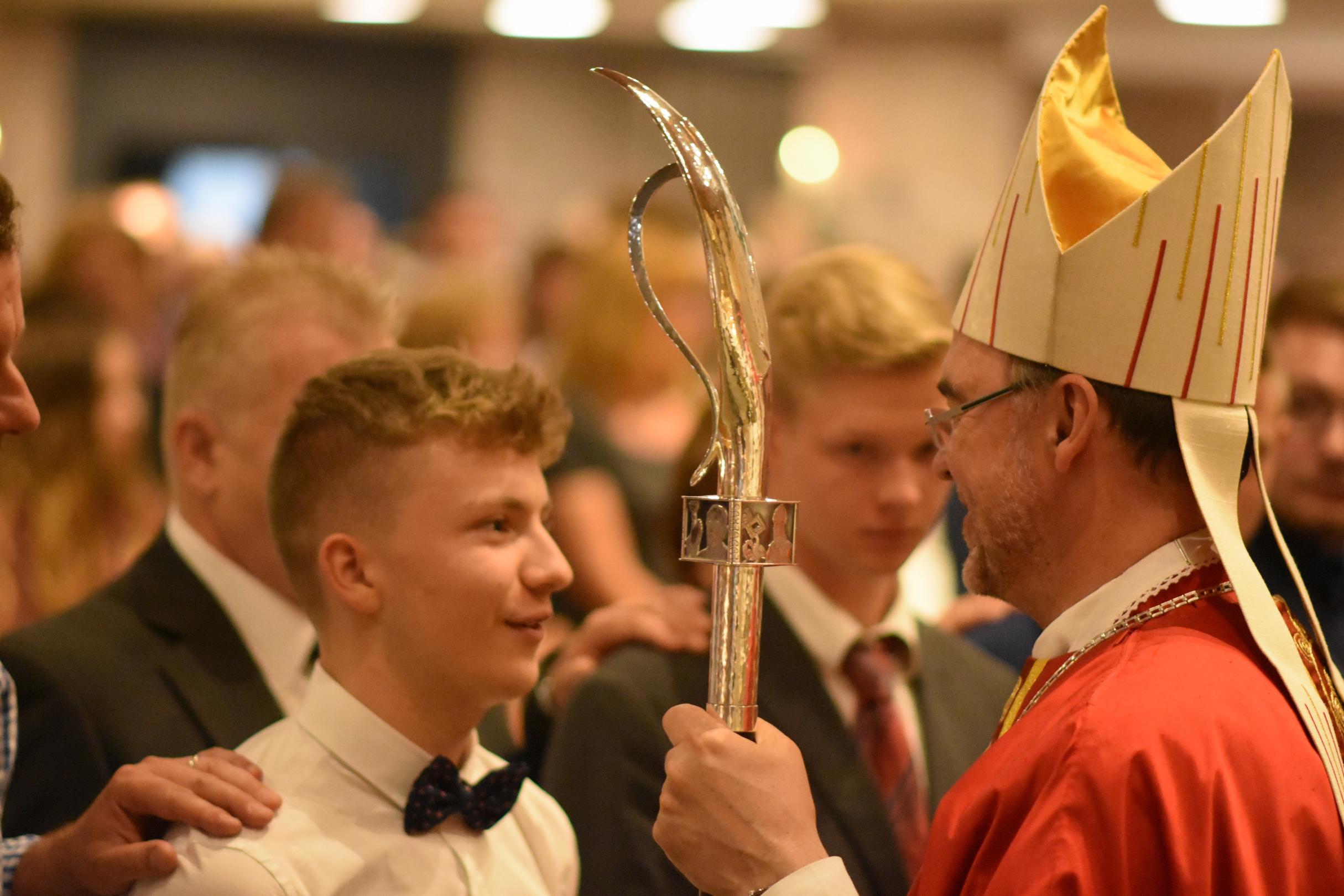 Ein Weihbischof spendet einem jungen Firmling die Firmung
