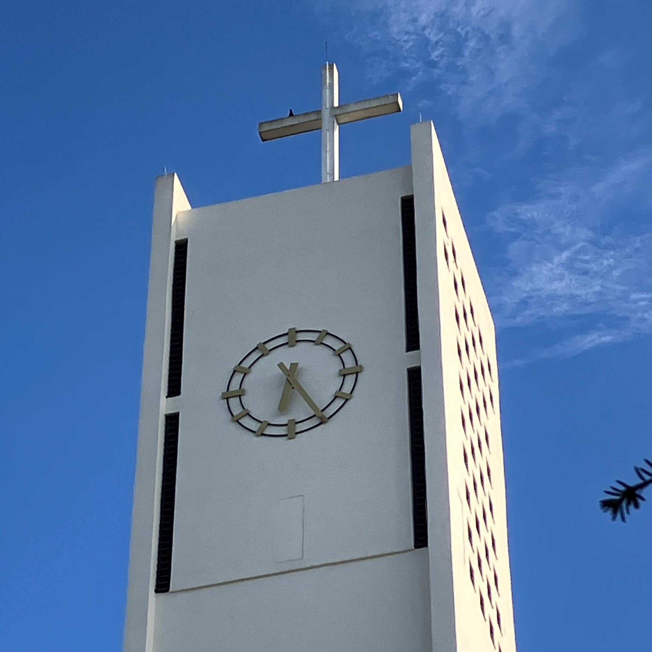 Kirchturm der Kirche Hl. Rosenkranzkönigin Merchweiler. Man sieht den oberen Teil mit der Uhr und dem Kreuz.