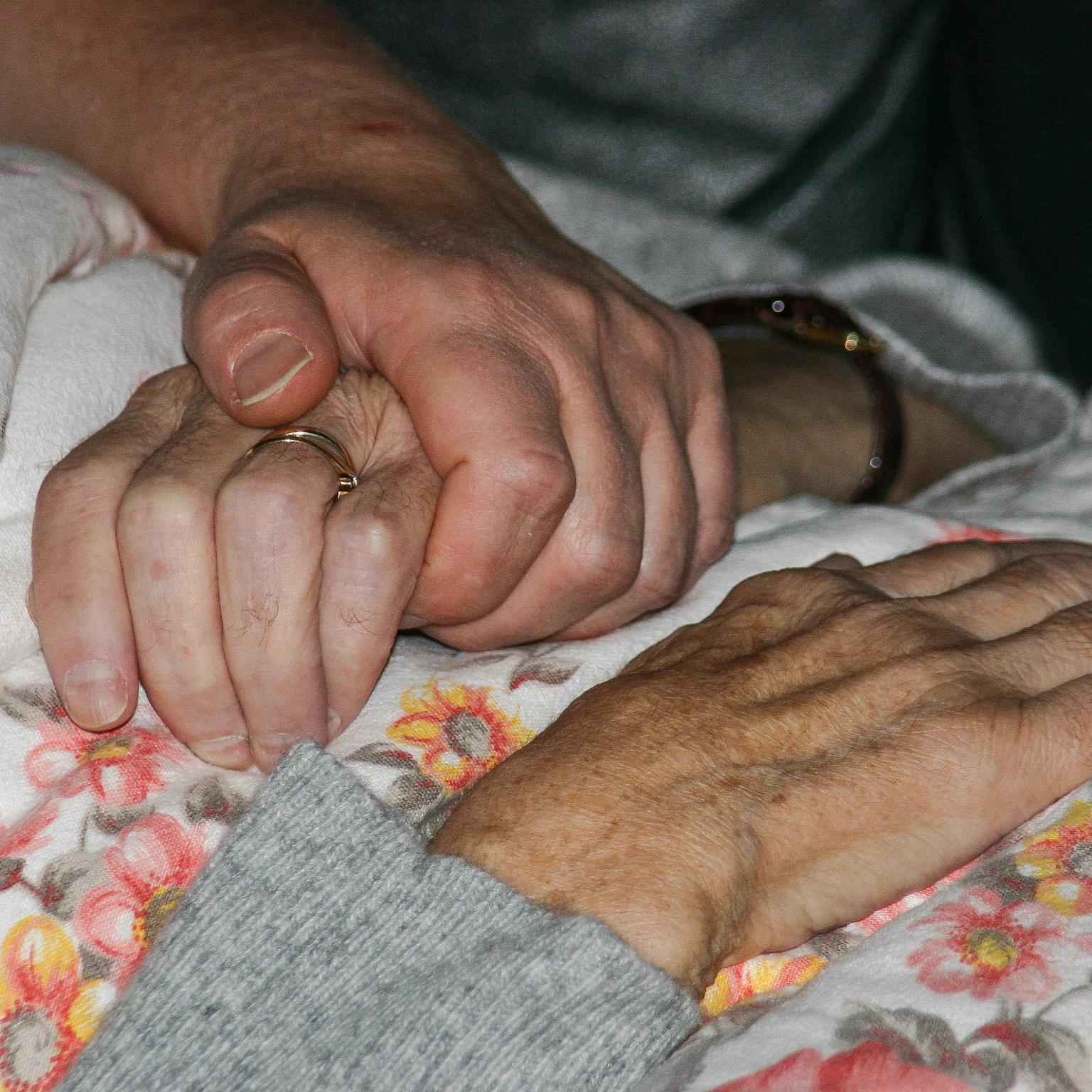 Ein Seelsorger besucht eine kranke Person am Krankenbett