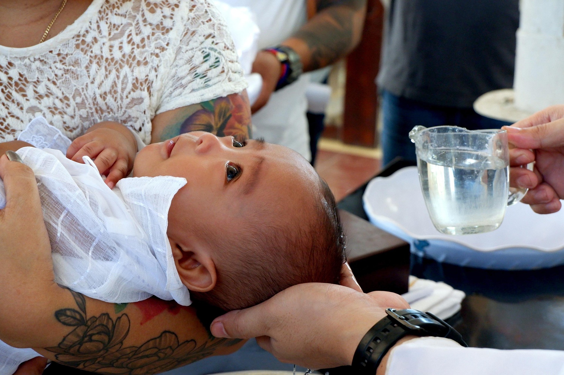 Ein Baby wird mit Weihwasser getauft