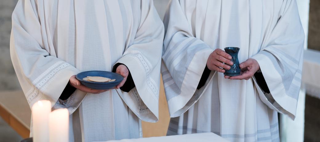 Zwei Messdiener in weißen roben bringen Brot und Wein zum Altar