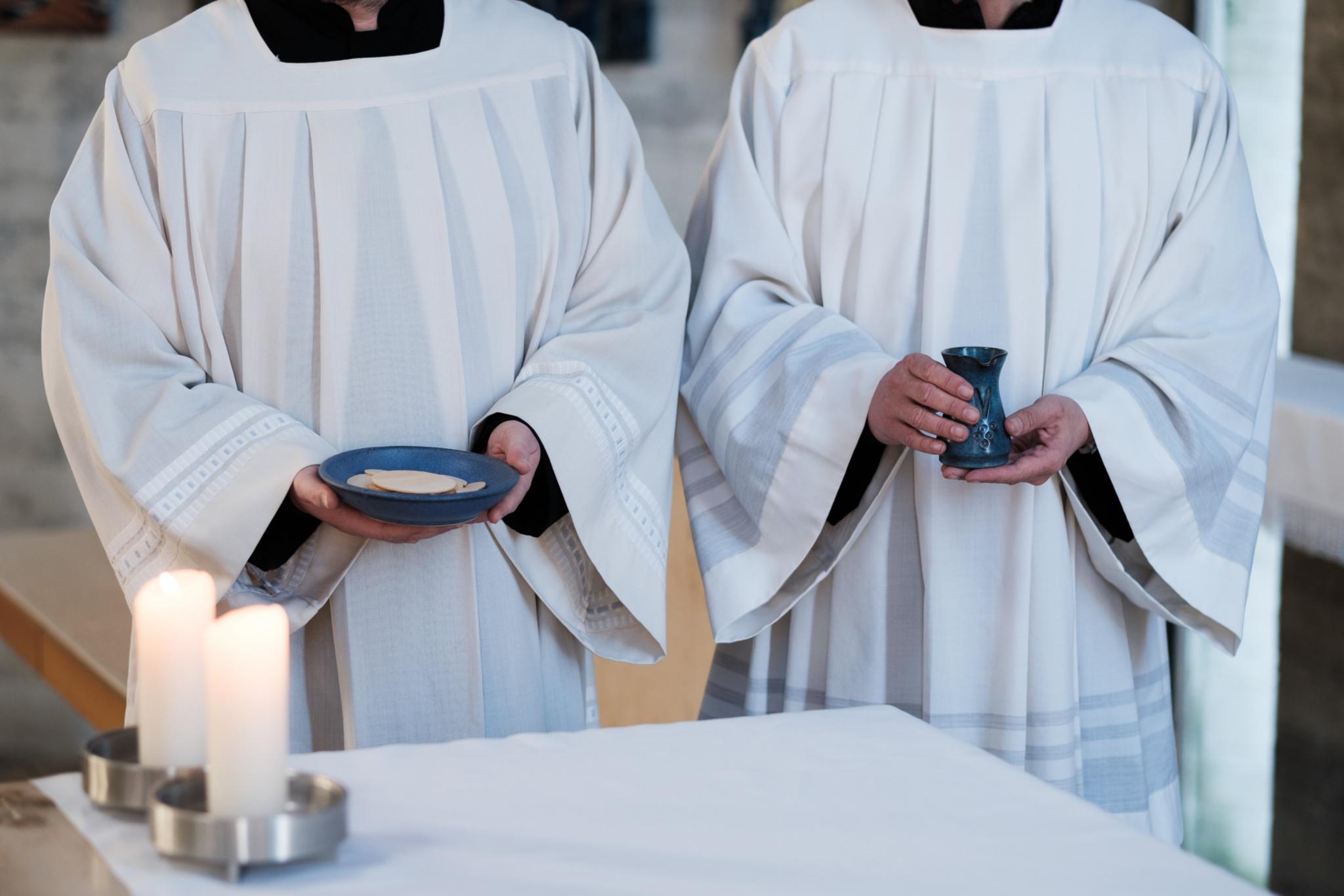 Zwei Messdiener in weißen roben bringen Brot und Wein zum Altar